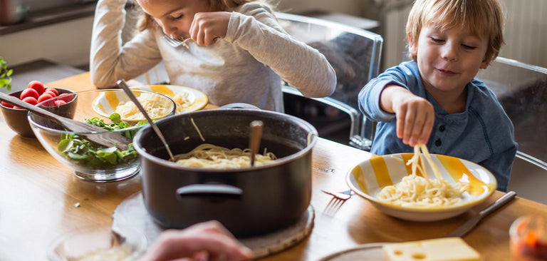 Children eating pasta at table